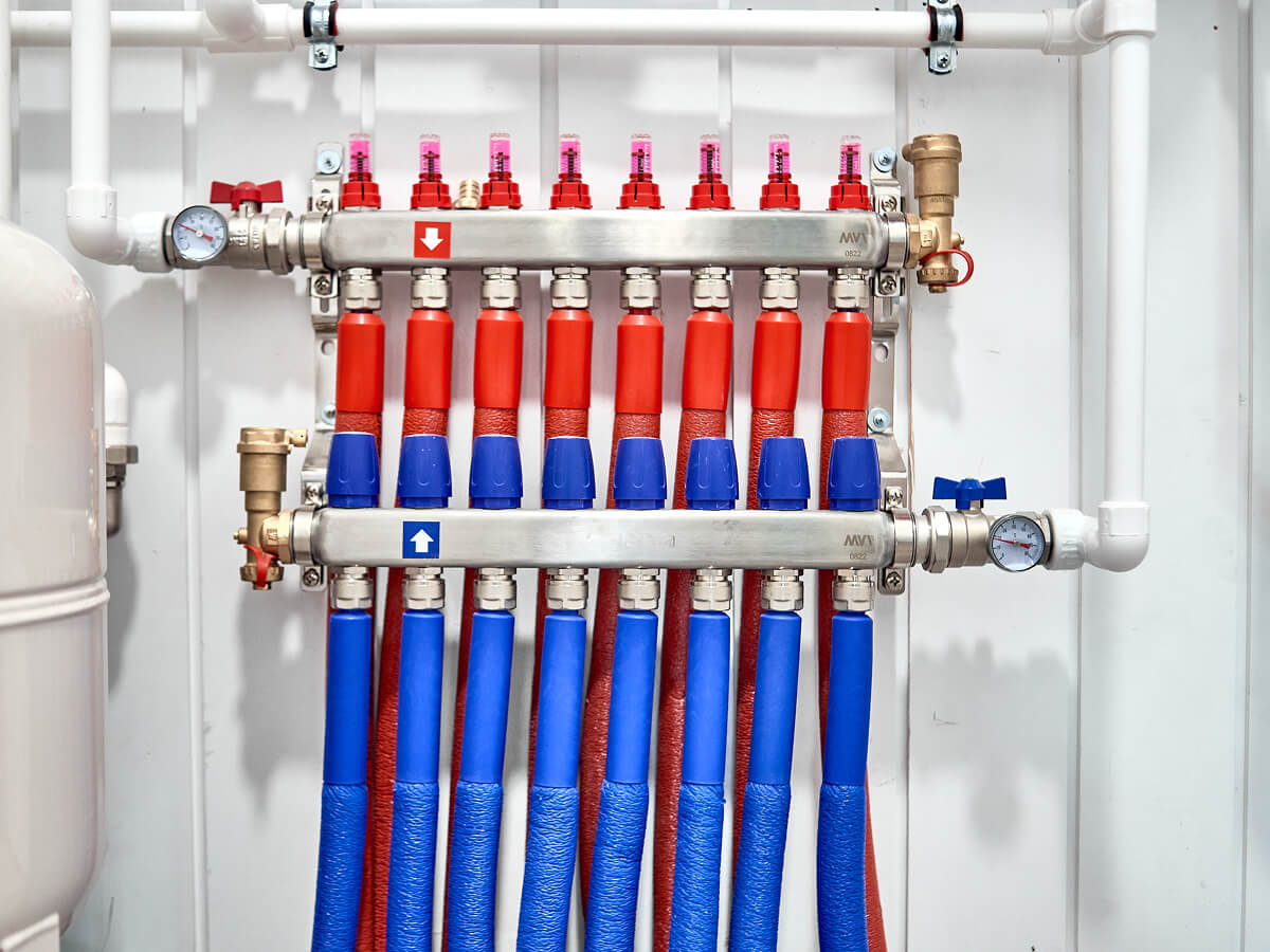 Коллекторный узел отопления с разноцветными трубами подачи и обратки